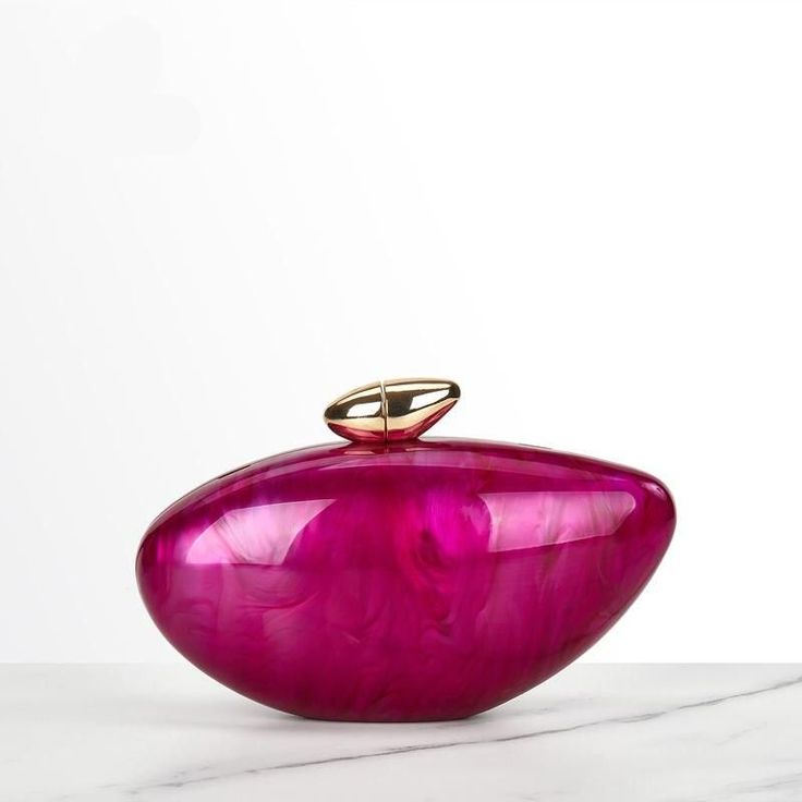 a pink vase sitting on top of a white counter next to a marble slab with a gold handle