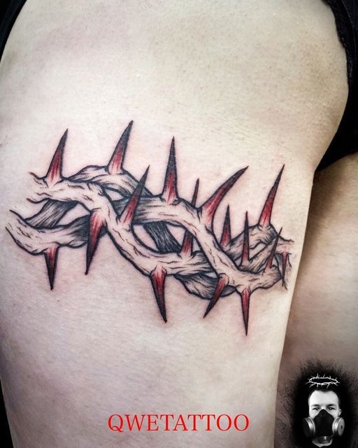 a tattoo on the back of a woman's thigh, with barbed wire around it