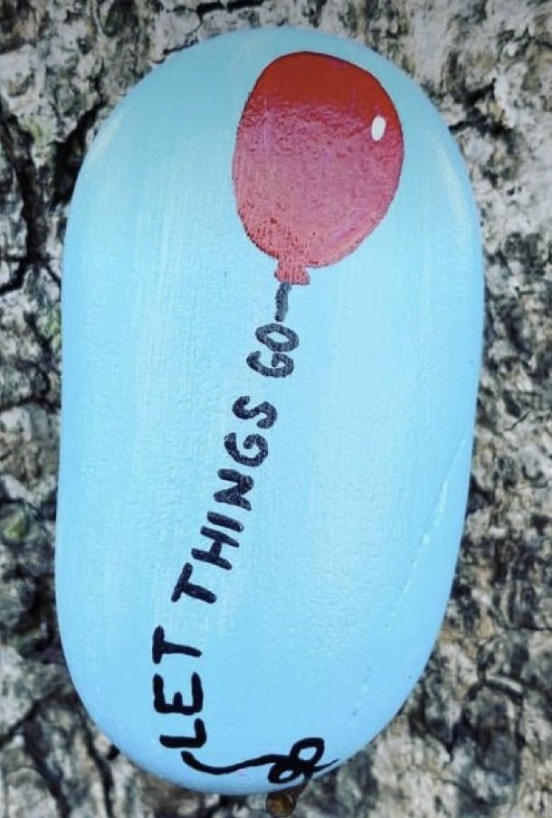 a painted rock with the words let things go written on it and a balloon attached to it