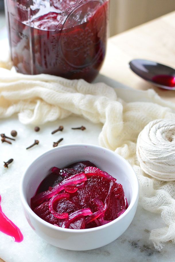 a white bowl filled with red liquid next to yarn