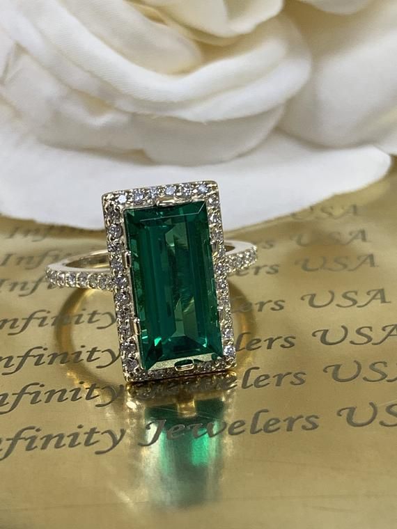 Baguette cut emerald unique fashion ring, with diamond halo and diamond accents 14k yellow gold # 5971 #FashionRing #BirthdayGift #EngagementRing #LadiesRing #BaguetteStone #DiamondHalo #EmeraldRing #MayBirthstone #TravelRing #UniqueRing Green Emerald-cut Ring With Halo Design, Green Emerald Cut Ring With Halo Design, Green Emerald-cut Halo Ring For Promise, Green Emerald Cut Halo Ring With Gemstone, Green Emerald Baguette Cut Diamond Ring, Green Moissanite Baguette Cut Diamond Ring, Green Moissanite Diamond Ring Baguette Cut, Green Moissanite Emerald Ring With Baguette Cut, Green Emerald Halo Diamond Ring