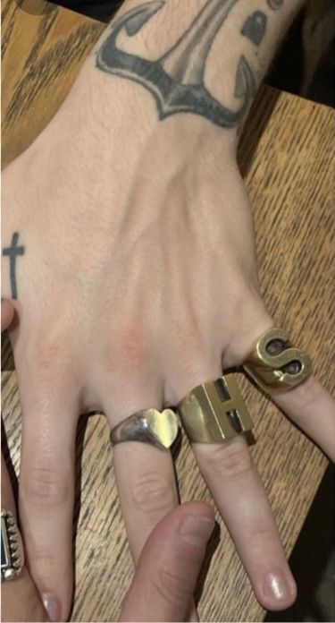 two people with tattoos on their hands holding onto each other's fingers and wearing rings