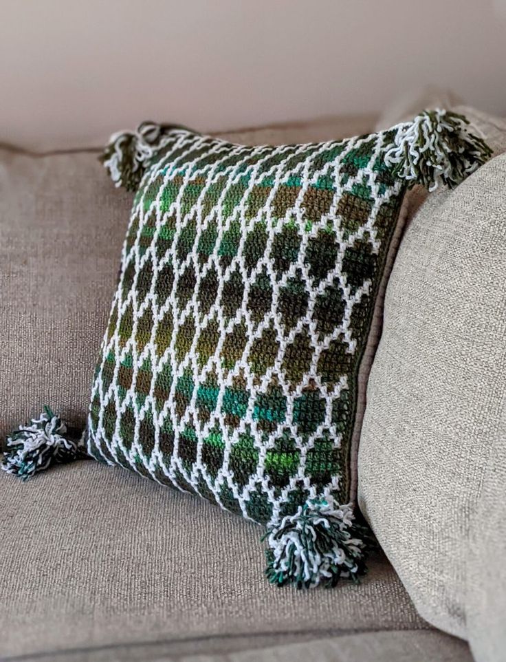 a close up of a pillow on a couch with a tasseled edge and pom poms