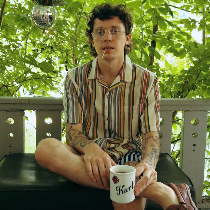 a man sitting on a bench holding a coffee cup