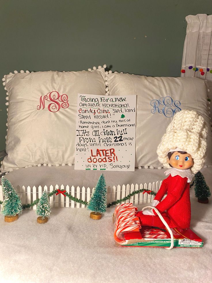 an elf sitting on top of a bed next to christmas trees and candy canes