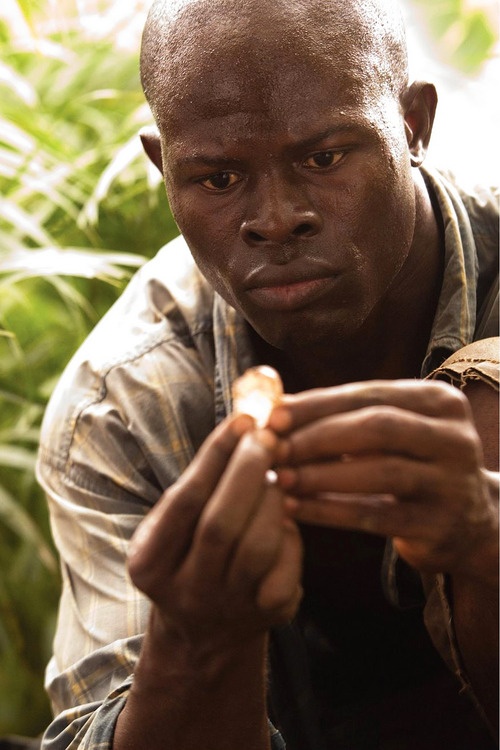 a man is looking at his cellphone while sitting in front of some green plants