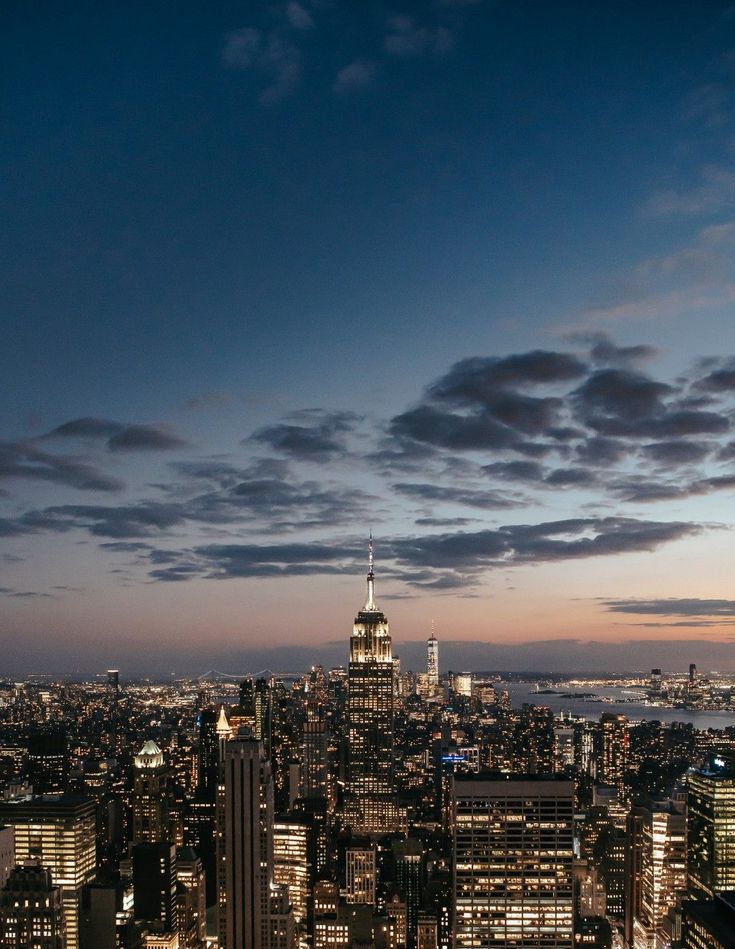 the city skyline is lit up at night, with skyscrapers in the foreground