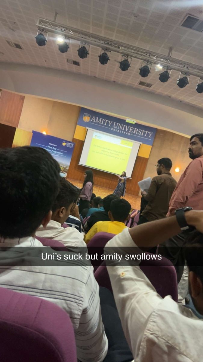 several people sitting in chairs and one person standing up with his hand out to the crowd