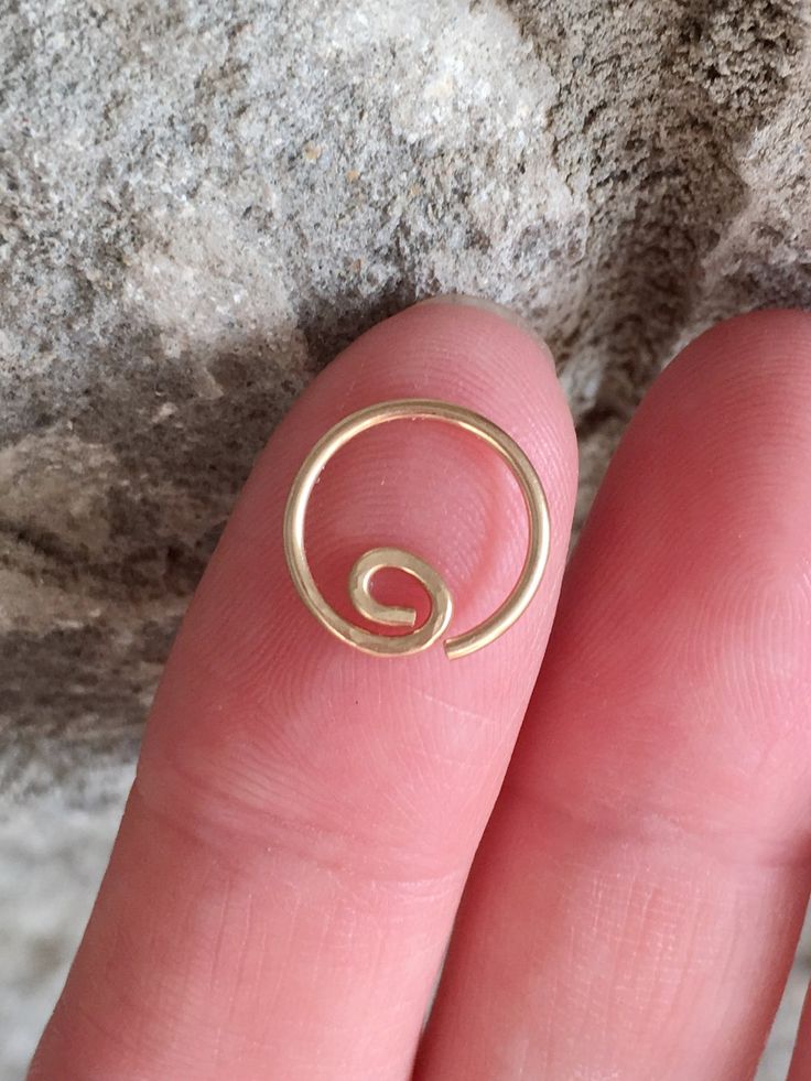 a person's finger with a gold spiral ring on top of their thumb and fingers