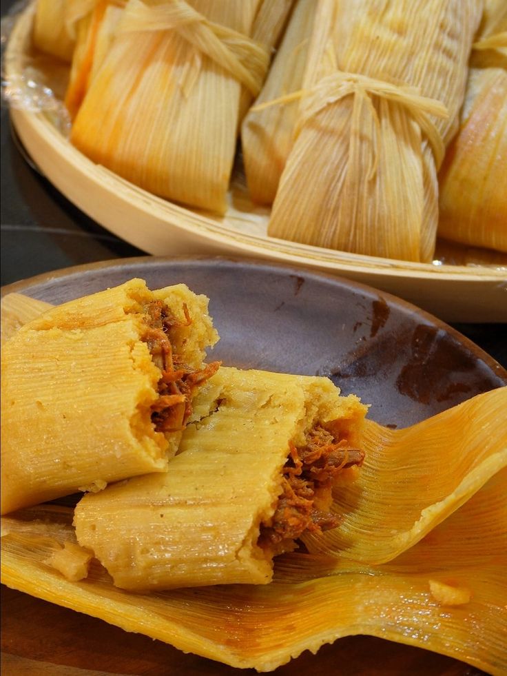 tamales with meat and cheese on a plate next to another plate full of tamales