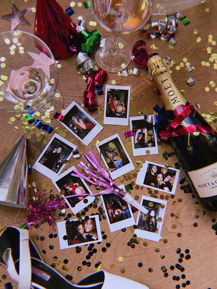 a table topped with champagne bottles and pictures next to confetti, streamers and party hats