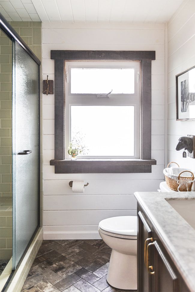 a white toilet sitting next to a bathroom sink under a window in a small room