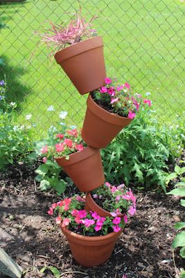 three flower pots are stacked on top of each other in the garden with pink and purple flowers