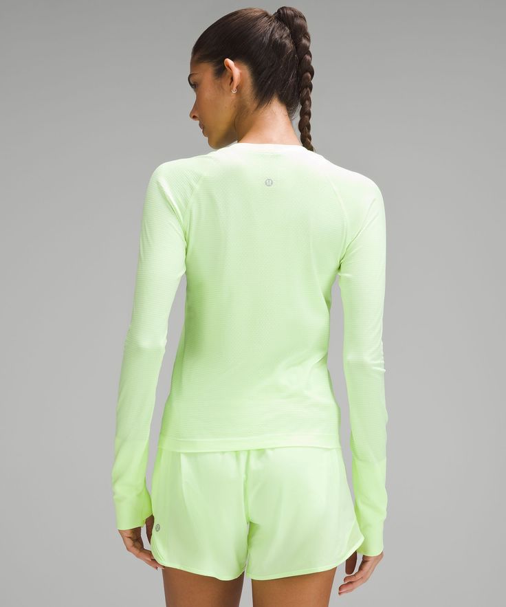 the back view of a woman wearing neon green shorts and a long sleeved top