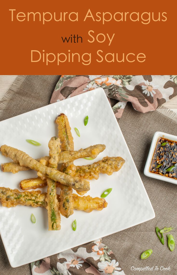 tempura asparagus with soy dipping sauce on a white plate next to small dishes