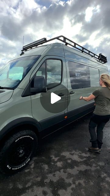 a woman standing in front of a van with the roof rack on it's side