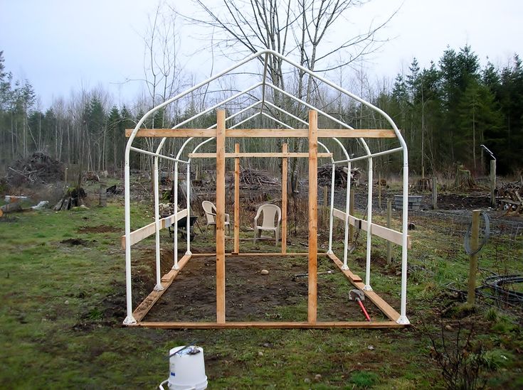 a chicken coop in the middle of an open field with trees and grass around it