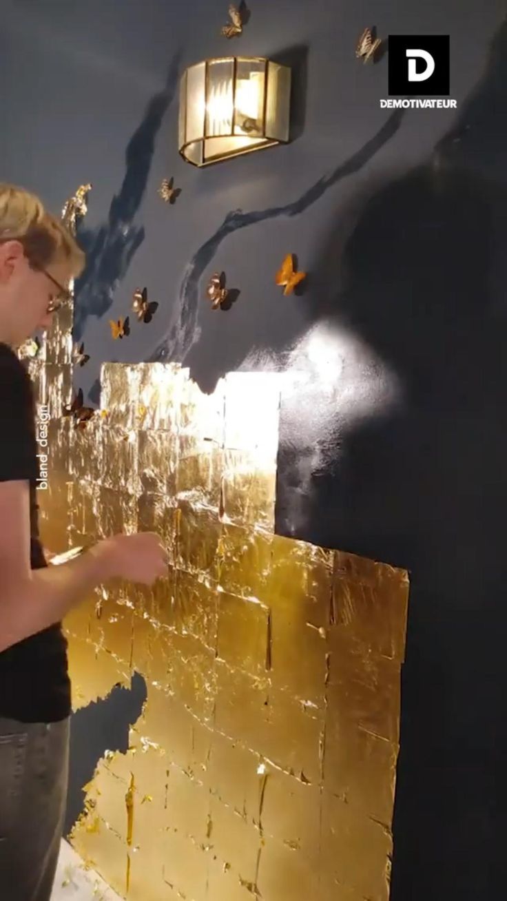 a man standing in front of a blue wall with gold foiled paint on it