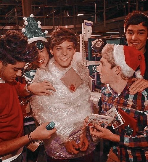 a group of young men standing next to each other in front of a christmas tree