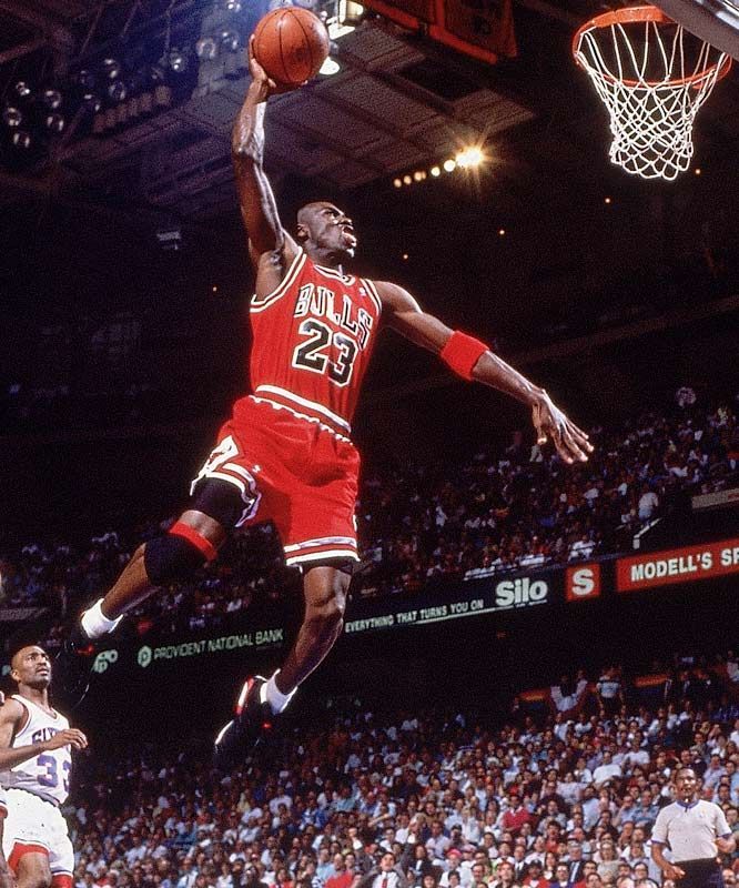 an old photo of a basketball player jumping in the air to dunk at a ball