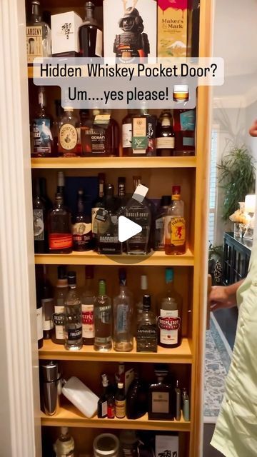 a man standing in front of a wooden shelf filled with liquor bottles and other items