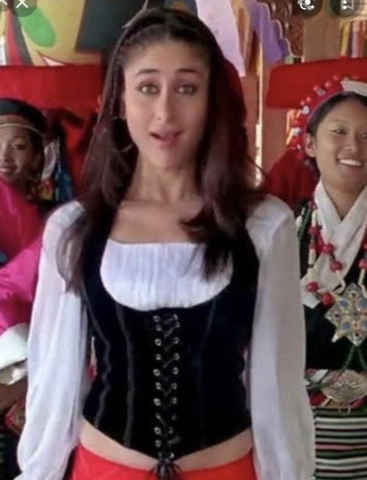 a woman in a corset standing next to other women wearing colorful clothing and smiling