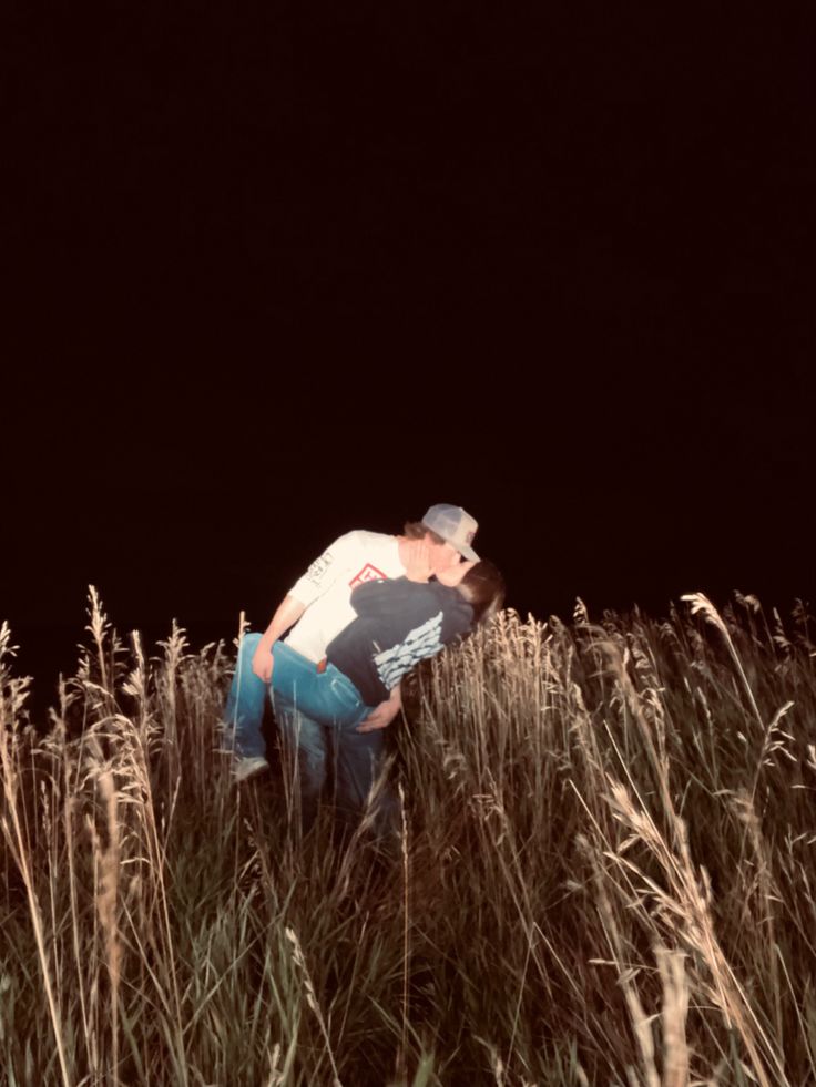 a man kneeling down in tall grass at night