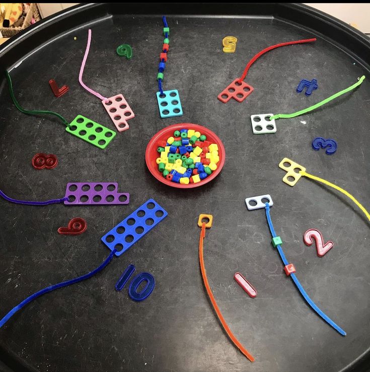 a black tray with lots of colorful beads and plastic numbers on it's surface