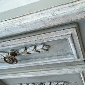 an old white painted cabinet with decorative knobs on the door handles and drawer pulls