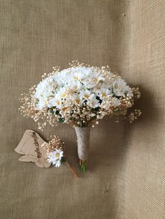 a bouquet of white flowers sitting on top of a piece of cloth next to a pair of shoes