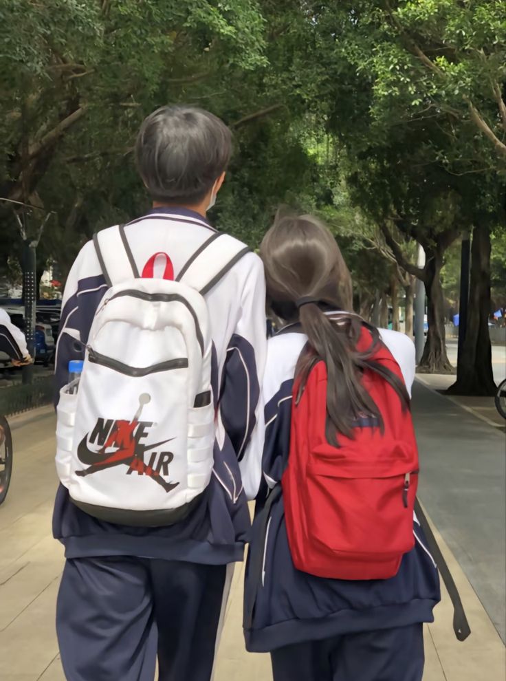 two children are walking down the sidewalk with backpacks