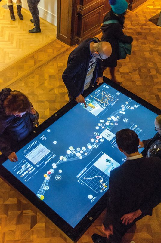 people standing around a table with a large screen on it