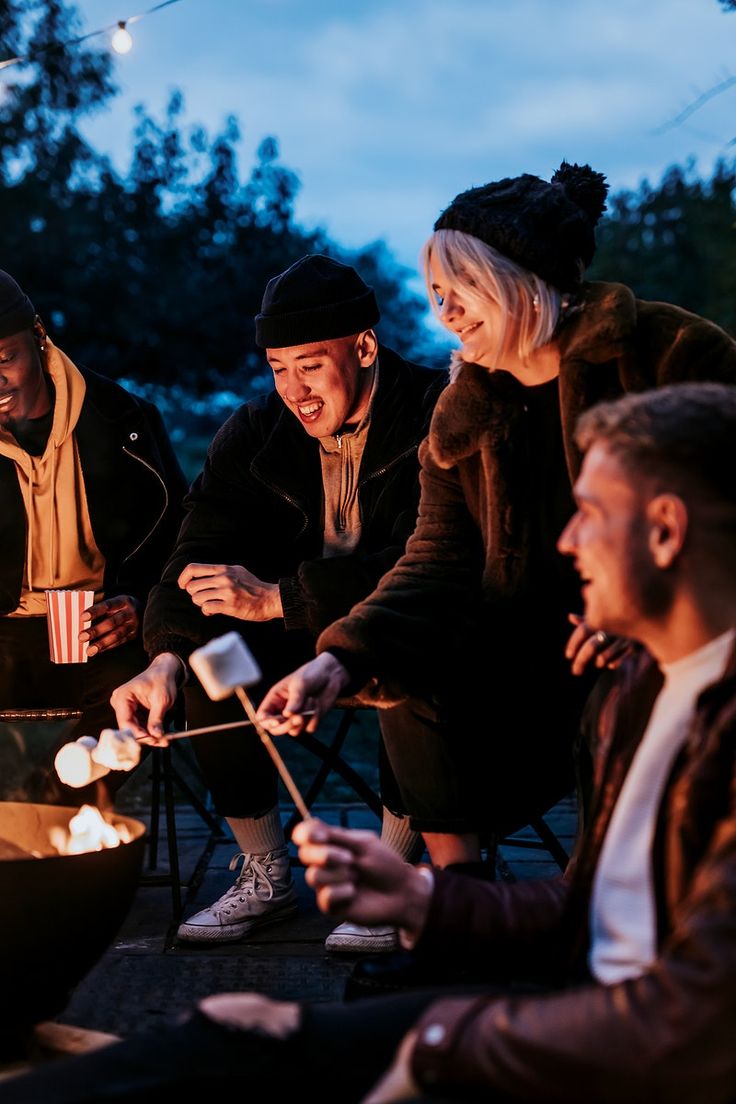 four people sitting around a campfire with marshmallows