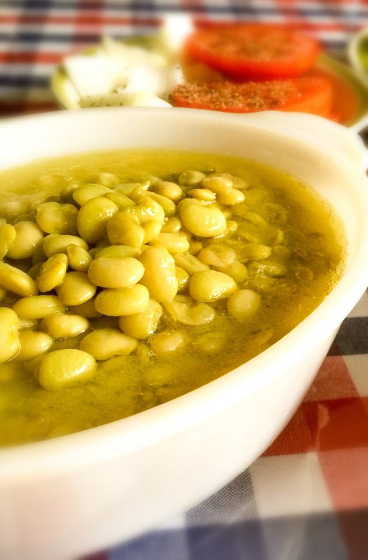 a white bowl filled with green beans on top of a checkered table cloth