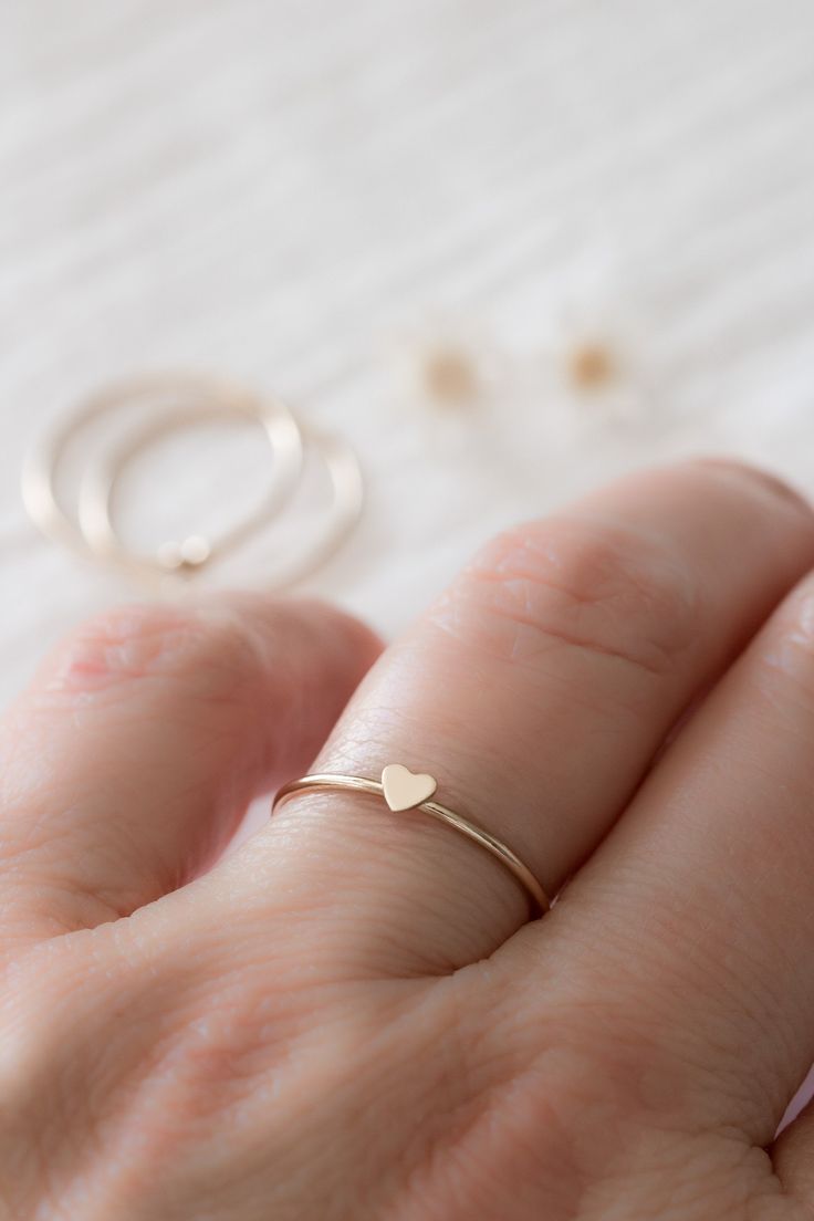 "This adorable and dainty heart ring is the perfect gift for you or someone special. With its matte, satin finish of solid 14k yellow gold, this petite heart creates a warm and romantic look, perfect for everyday wear or special occasions. A great way to celebrate a friendship, honor your bridesmaids, or say \"I love you\" to family. The perfect gift for mom, stack one for each of her loves! ❤️ ✥ Solid 14k yellow gold ✥ Ethically sourced ✥ Beautifully boxed ✥ Gift wrap available at checkout ✥ Ha Delicate Stackable Promise Rings For Valentine's Day, Simple Tiny Heart Ring For Anniversary, Dainty Stackable Gift Rings With Heart Charm, Minimalist Stackable Rings With Heart Charm For Anniversary, Dainty Heart Charm Stackable Gift Rings, Minimalist Stackable Rings With Heart Charm For Wedding, Stackable 14k Gold Heart Ring For Valentine's Day, 14k Gold Stackable Heart Ring For Valentine's Day, Minimalist Rings With Heart Charm For Everyday