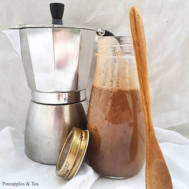 a wooden spoon sitting next to a coffee pot and measuring cup on a white cloth