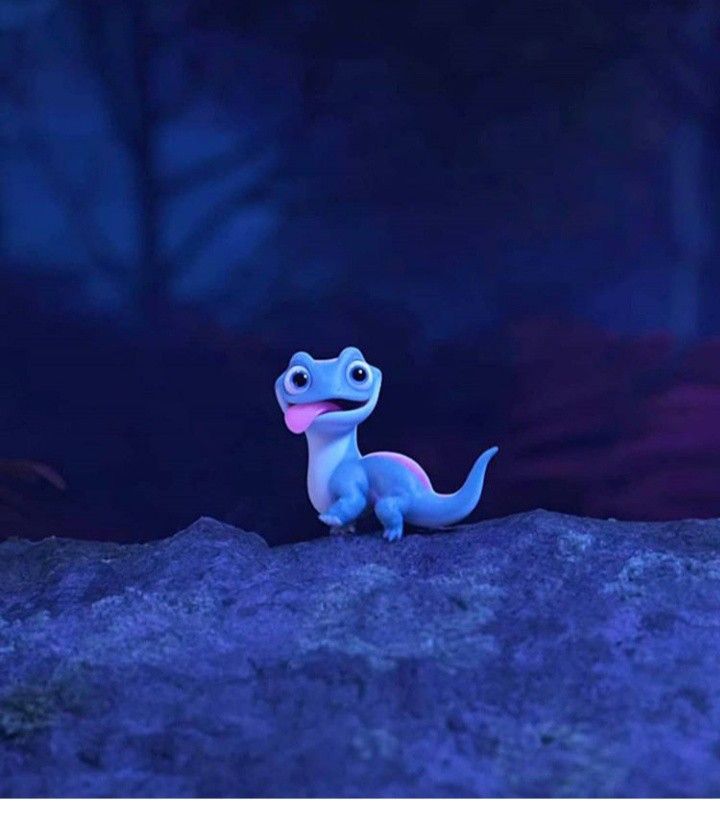 a small toy dinosaur sitting on top of a rock in the dark night with its tongue out