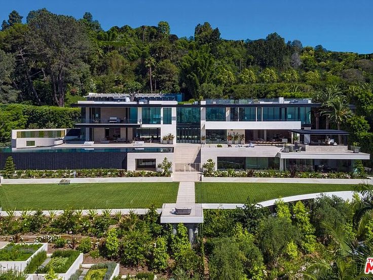 an aerial view of a large house in the middle of trees and grass, surrounded by lush