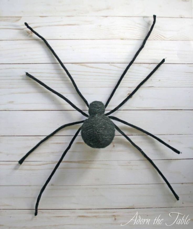 a spider made out of yarn sitting on top of a white wooden floor with the words,