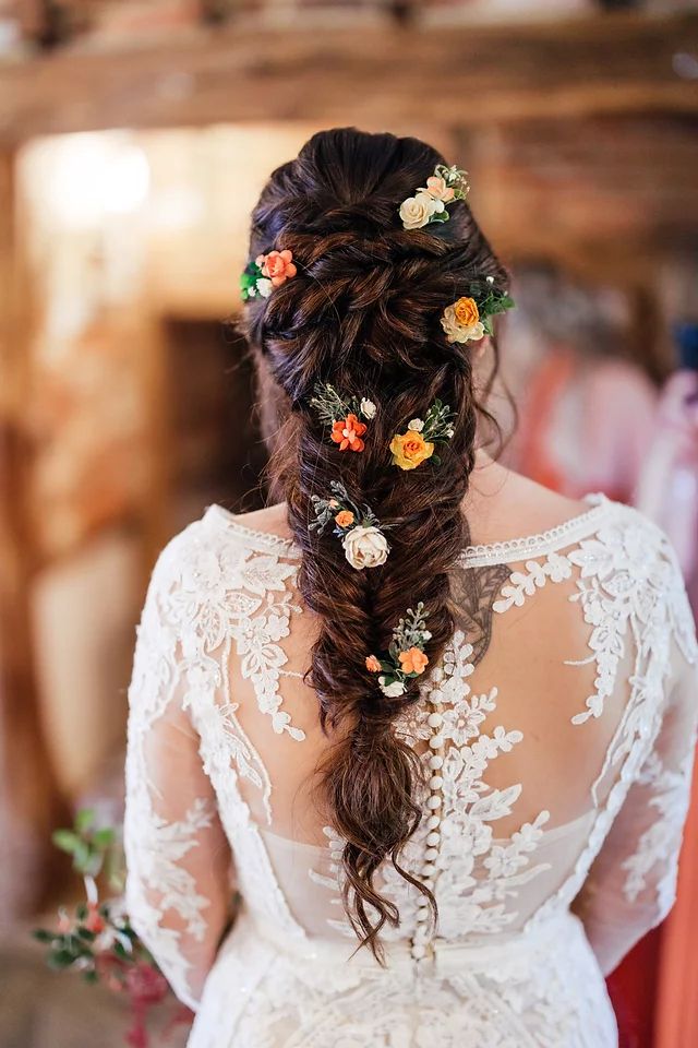 the back of a bride's head with flowers in her hair and an intricate braid