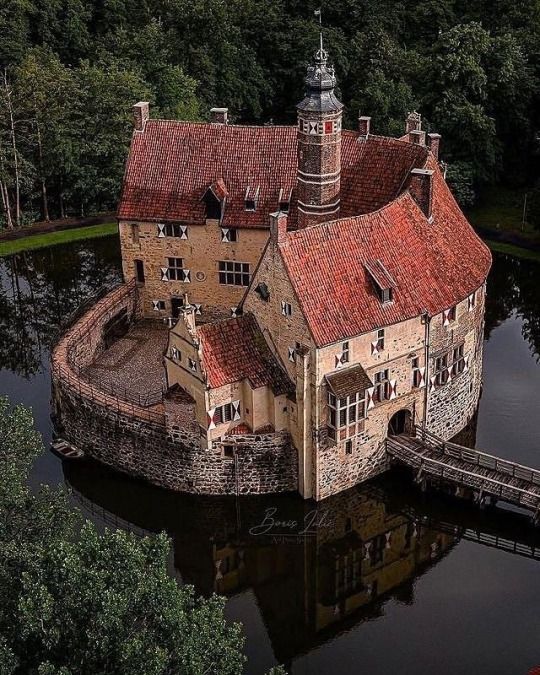 an old castle sits in the middle of a lake surrounded by trees and greenery