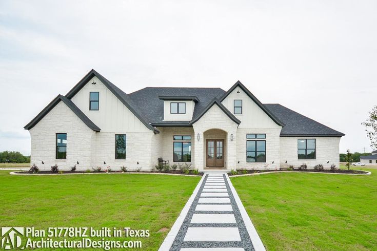 a large white house sitting in the middle of a lush green field on a cloudy day