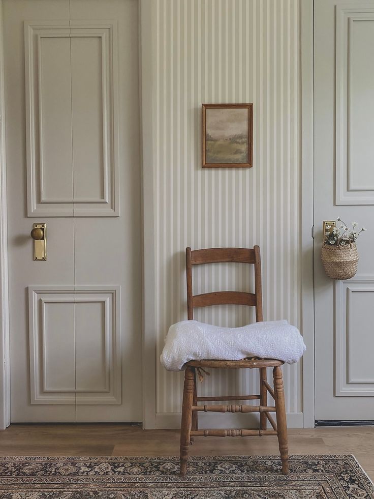 a chair sitting in front of a door with a rug on the floor next to it