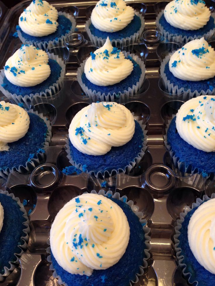 cupcakes with white frosting and blue sprinkles in a muffin tin