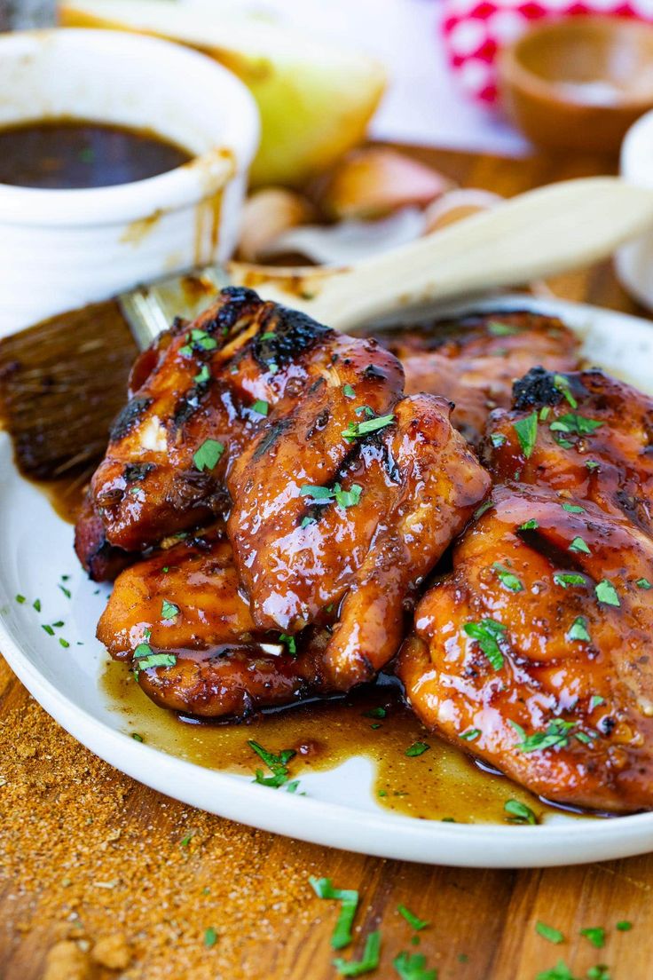 two chicken wings on a plate with sauce and parsley