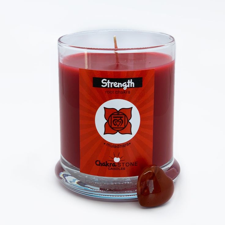 a red candle with a heart shaped candy in it's glass holder on a white background