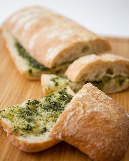 two pieces of bread with pesto and cheese on them sitting on a cutting board