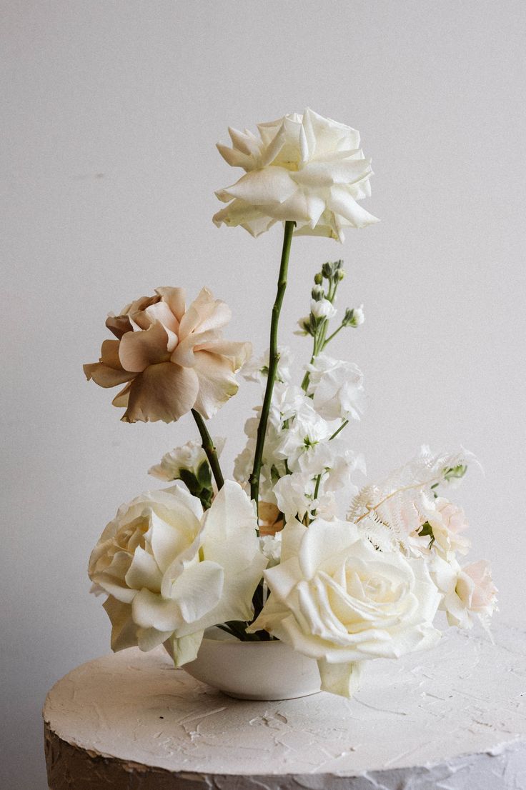 a white vase with flowers on top of a table