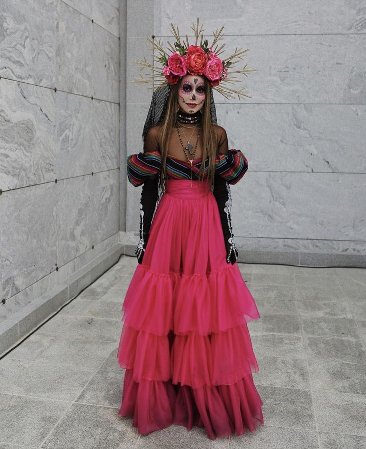 a woman in a long pink dress with flowers on her head