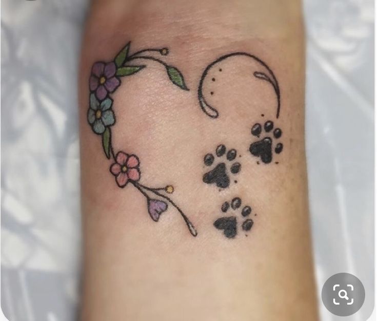 a small tattoo on the arm of a person with a dog's paw and flower